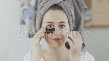 女人头上戴着毛巾，眼睛下面贴着一块清爽的<strong>胶原蛋白</strong>水解<strong>面膜</strong>。